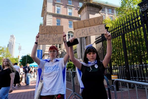 Freshman Columbia and Barnard students Lila and Shoshana, who are Jewish, hold up signs as they counter-protest pro-Palestinian supporters outside Columbia University 