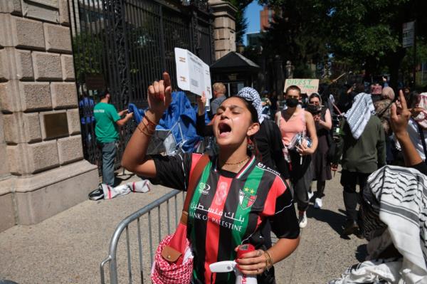 A woman participating in a Pro-Palestine protest outside Barnard College of Columbia University, holding a sign and pointing, on the first day of fall semester classes, September 3, 2024.