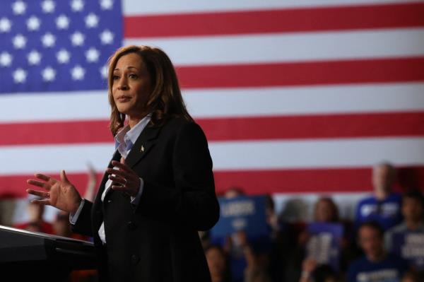 Kamala Harris speaks on stage with an American flag backdrop.