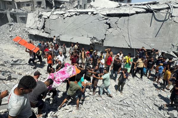 Palestinians carrying a casualty amid rubble of destroyed houses following an Israeli strike in Khan Younis, southern Gaza Strip, August 27, 2024