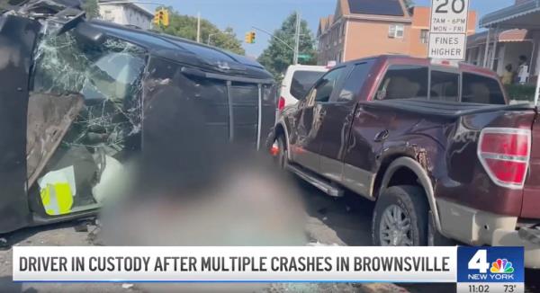 A black minivan with a smashed window is flipped on its side next to another damaged car