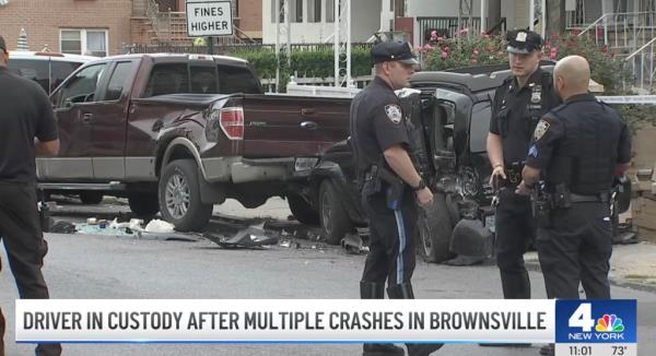 Police officers stand next to smashed cars